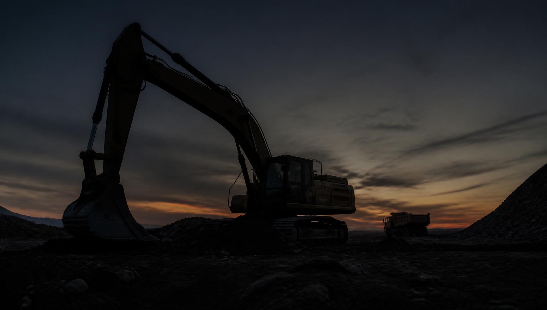 Excavator silhouetted against a dusk sky on a New Jersey construction site