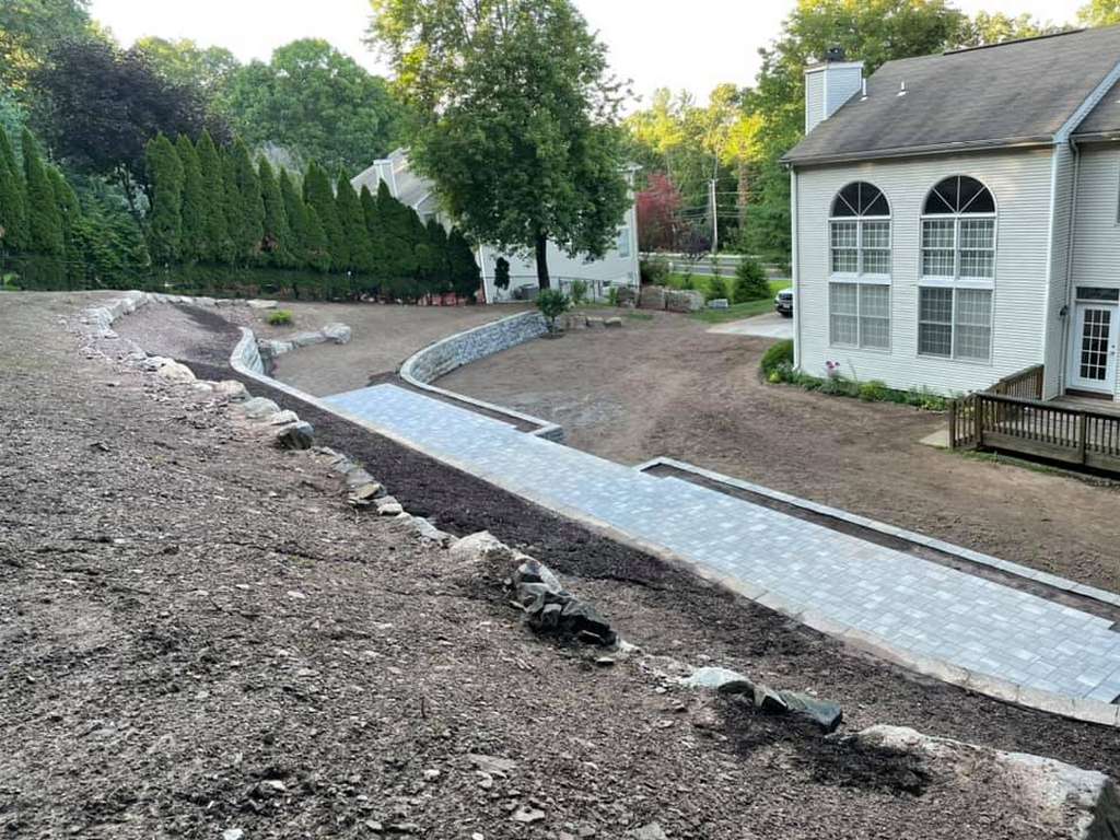 Curved paver driveway and entry walkway installed at a white residential home