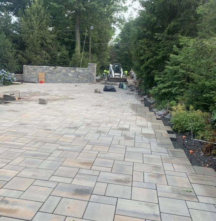 Large-format paver patio and walkway running along a stone retaining wall