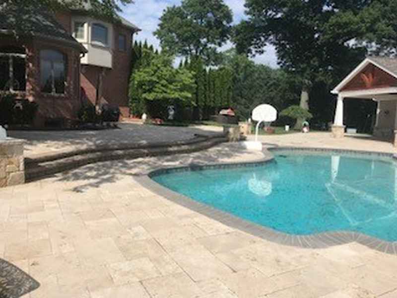 Travertine pool patio surrounding an in-ground pool with a covered pavilion